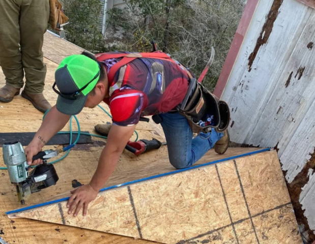 Worker using tools on a house to install a roof